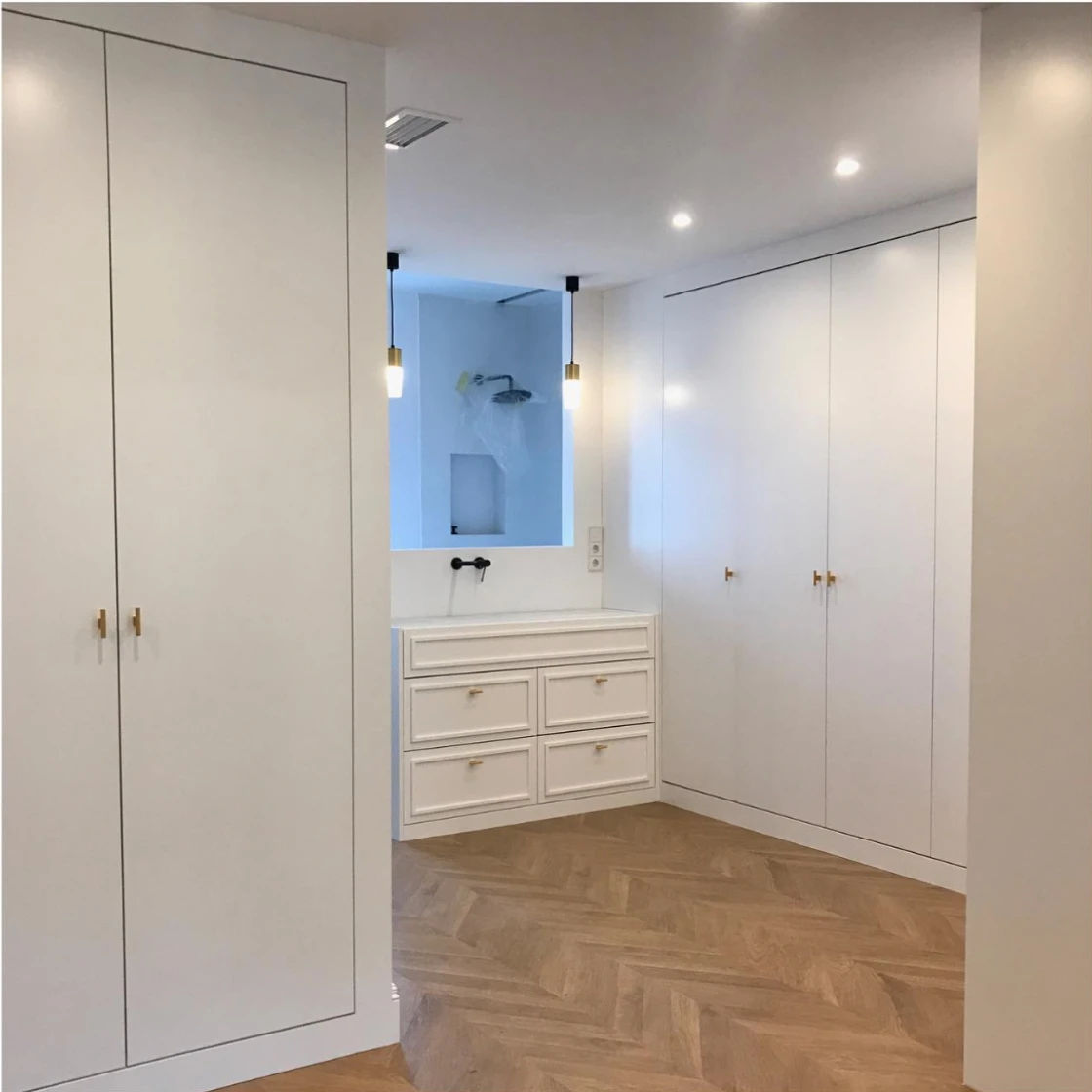 Imagen de un armario y cómoda de color blanco sobre parquet