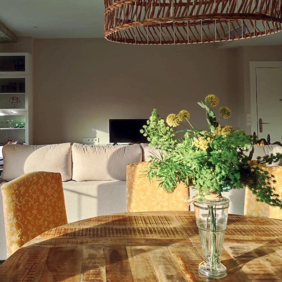 Imagen de un sofá y una mesa con un jarrón y un ramo de flores